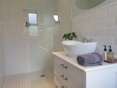 a white bathroom with a sink and a shower at Tram View Hideaway in Franschhoek