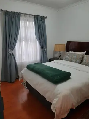 a bedroom with a large bed with a green blanket at Local & Comfortable in Mandalay