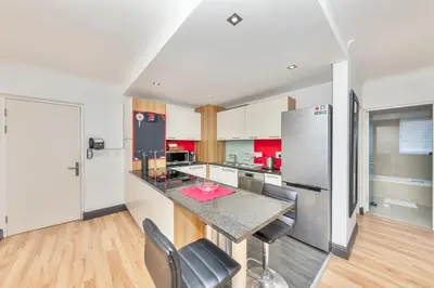 a kitchen with a counter with chairs and a refrigerator at Horizon Bay 201-Beachfront Gem Table Mtn in Cape Town
