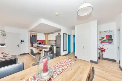 a living room with a table and a kitchen at Horizon Bay 201-Beachfront Gem Table Mtn in Cape Town