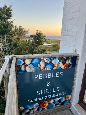 a sign for pebbles and shells on a building at Pebbles & Shells in Kleinmond