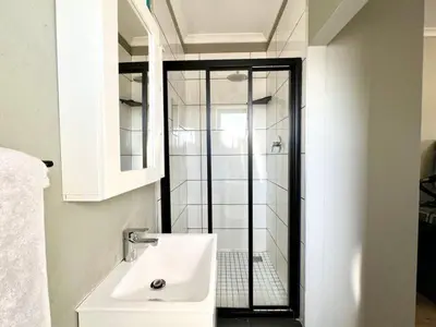 a bathroom with a sink and a glass shower at Cape on Porterfield in Cape Town