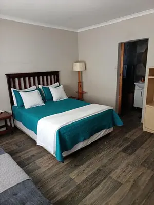 a bedroom with a large bed with blue and white pillows at Bluehaven self-catering guesthouse in Hermanus
