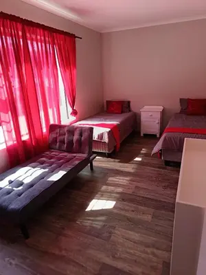 a bedroom with two beds and red curtains at Bluehaven self-catering guesthouse in Hermanus