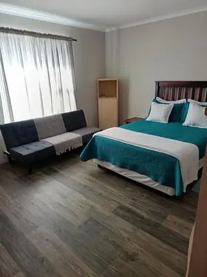 a bedroom with a large bed and a couch at Bluehaven self-catering guesthouse in Hermanus