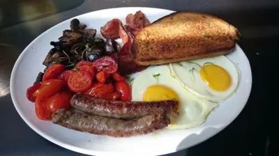 a plate of breakfast food with sausage eggs and toast at The Bridgewater collection 411- Luxury 1 bed Morden Apartment at Century City in Cape Town