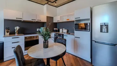 a kitchen with a table with chairs and a refrigerator at The Bridgewater collection 411- Luxury 1 bed Morden Apartment at Century City in Cape Town