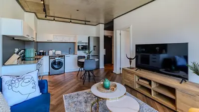 a living room with a blue couch and a kitchen at The Bridgewater collection 411- Luxury 1 bed Morden Apartment at Century City in Cape Town