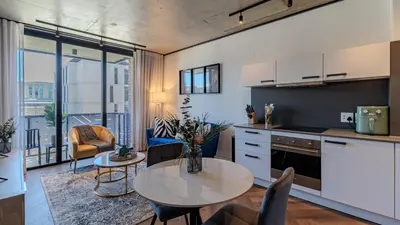 a kitchen and living room with a table and chairs at The Bridgewater collection 411- Luxury 1 bed Morden Apartment at Century City in Cape Town