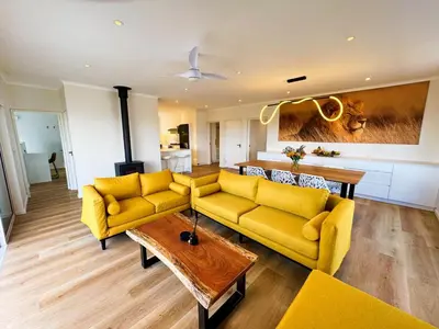 a living room with yellow couches and a table at Peach On Beach Boutique Apartments in Hermanus