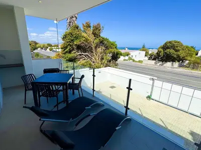 a balcony with a table and chairs and a view of a street at Peach On Beach Boutique Apartments in Hermanus