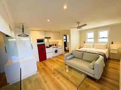 a bedroom with a bed and a couch and a table at Peach On Beach Boutique Apartments in Hermanus