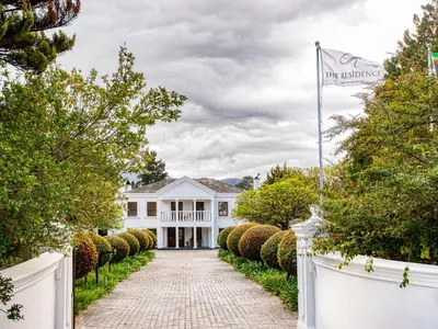 a white house with a white fence and a driveway at The Residence Boutique Hotel in Grabouw