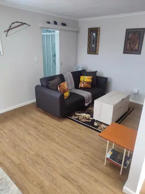 a living room with a black couch and a table at Birds Holiday Accommodation 1 in Zeekoevlei