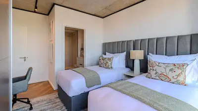 a bedroom with two beds and a desk and a chair at Bridgewater Serenity Collection 708 in Cape Town