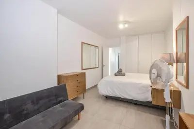 a bedroom with a bed and a couch and a fan at 2 Bedroom Apartment - Dolphin Beach in Cape Town