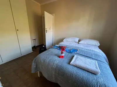 a bedroom with a bed with a blue bedspread and a bottle on it at Hermanus Hartshuis in Hermanus