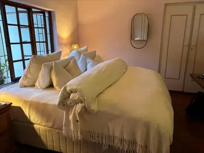 a bedroom with a bed with white sheets and pillows at Hermanus Hartshuis in Hermanus