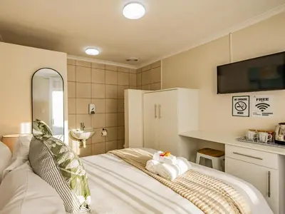 a bedroom with a bed with a tv on the wall at Olive Grove Bed & Breakfast in Kraaifontein