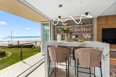 a kitchen with a table with chairs and a view of the ocean at Lagoon Beach Luxe 116A in Cape Town