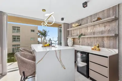 a kitchen with a white counter and some chairs at Lagoon Beach Luxe 116A in Cape Town