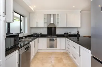 a kitchen with white cabinets and black counter tops at Luxury Lodge TheView, Pearl Valley Golf Estate in Paarl