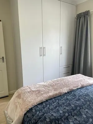 a bedroom with white cabinets and a bed at Parklands Family Stay in Cape Town