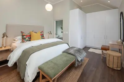 a bedroom with a large white bed and a table at Luxury Villa in Best Central Location in Franschhoek