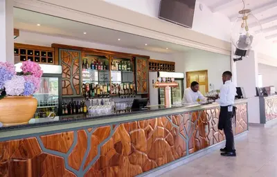 two men standing at a bar in a restaurant at Houw Hoek Hotel in Botrivier