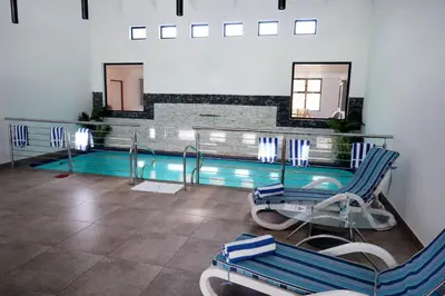a swimming pool with two chairs and a table at Houw Hoek Hotel in Botrivier