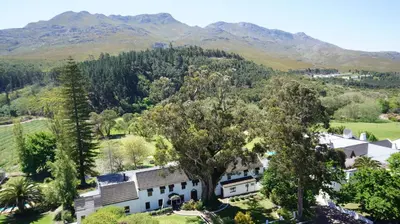an aerial view of a house with mountains in the background at Houw Hoek Hotel in Botrivier