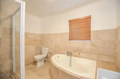 a bathroom with a tub and a toilet and a sink at Large 4 Bedroom Villa with Pool in Cape Town