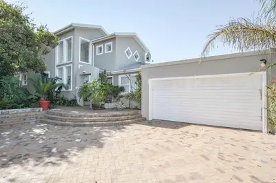 a large house with a white garage door at Large 4 Bedroom Villa with Pool in Cape Town