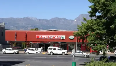 a kwikstaarma store with cars parked in front of it at House On Plein in Paarl