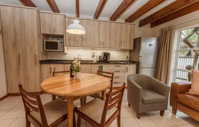 a kitchen and dining room with a table and chairs at Protea Garden Cottage in Stellenbosch