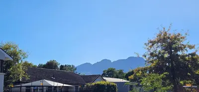 a house with mountains in the background at Protea Garden Cottage in Stellenbosch