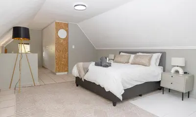 a bedroom with a large bed and a lamp at Home in Durbanville in Oakdale