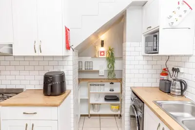 a small kitchen with white cabinets and a sink at Home in Durbanville in Oakdale