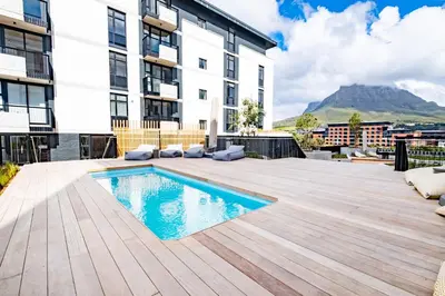an apartment patio with a swimming pool and a building at 413 Riverlands - 1 Bedroom Apartment with Parking in Cape Town