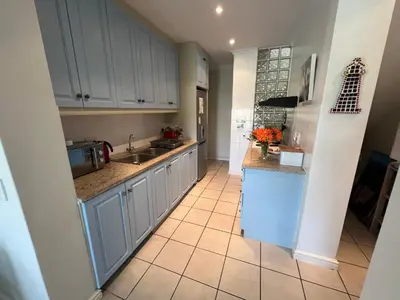 a kitchen with white cabinets and a tile floor at Golfers delight in Hermanus