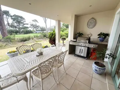 a patio with a table and chairs and a stove at Golfers delight in Hermanus