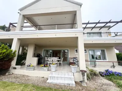 a house with a porch with tables and chairs at Golfers delight in Hermanus