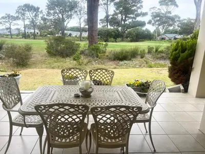 a table and chairs on a patio with a view at Golfers delight in Hermanus