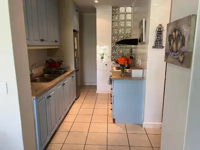 a kitchen with white cabinets and a tile floor at Golfers delight in Hermanus