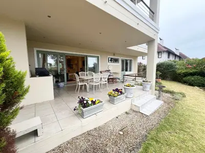 a patio with a table and chairs and flowers at Golfers delight in Hermanus