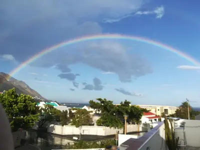 a rainbow in the sky over a city at Big Skies Guesthouse in Gordonʼs Bay