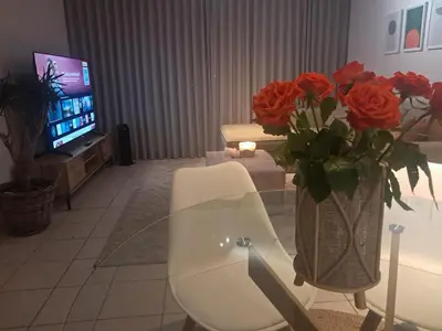 a living room with a table and a vase of roses at Salt & Sandy Shores Dolphin Beach Blouberg in Cape Town