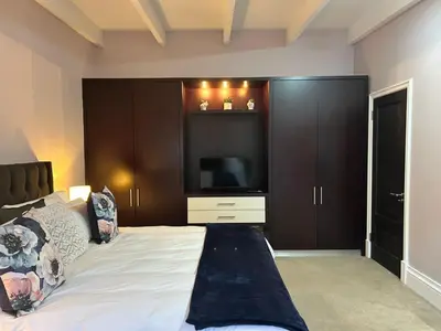 a bedroom with a large bed with a flat screen tv at Bishopsfield Guesthouse Rondebosch in Cape Town