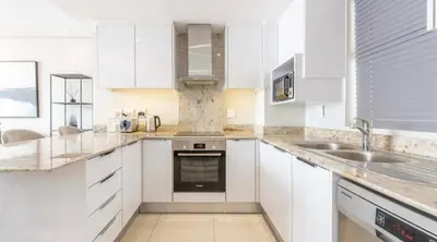 a white kitchen with white cabinets and a sink at Andringa Walk, Modern 2 Bedroom Apartment in Stellenbosch