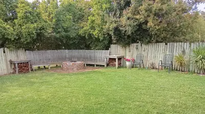 a backyard with a wooden fence and a table and chairs at Groendraai PetFriendly SelfCatering Accommodation, Die Karoohuis, Die Wijnhuis and Die Vinknes